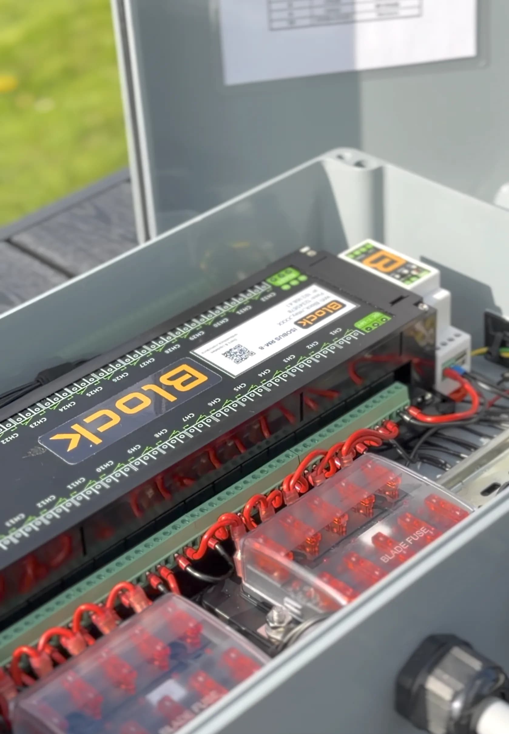 The Amazone build's enclosure open: the 32-channel module wired through two blade-fuse boxes, with the printed channel map in the lid