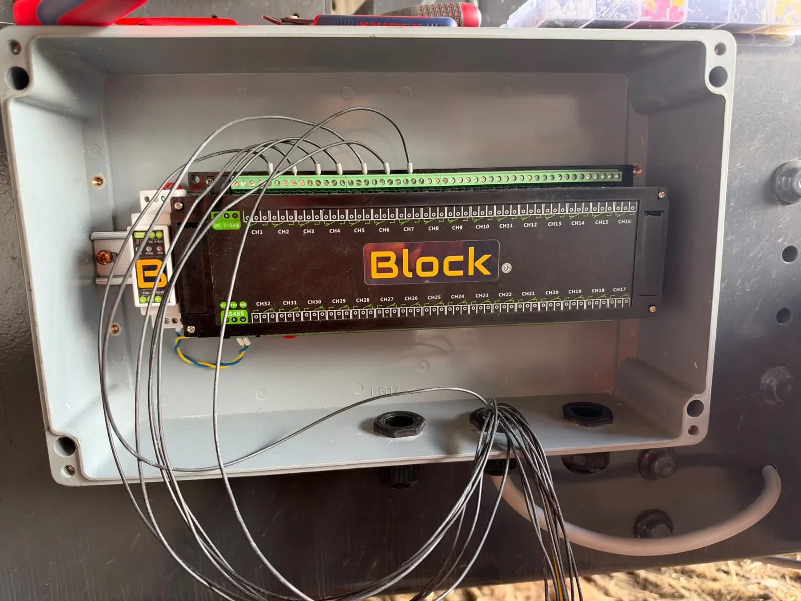 The empty grey enclosure on the trailer chassis with the 32-channel module and its CAN bridge on the DIN rail, the first load leads pulled in through the bottom glands