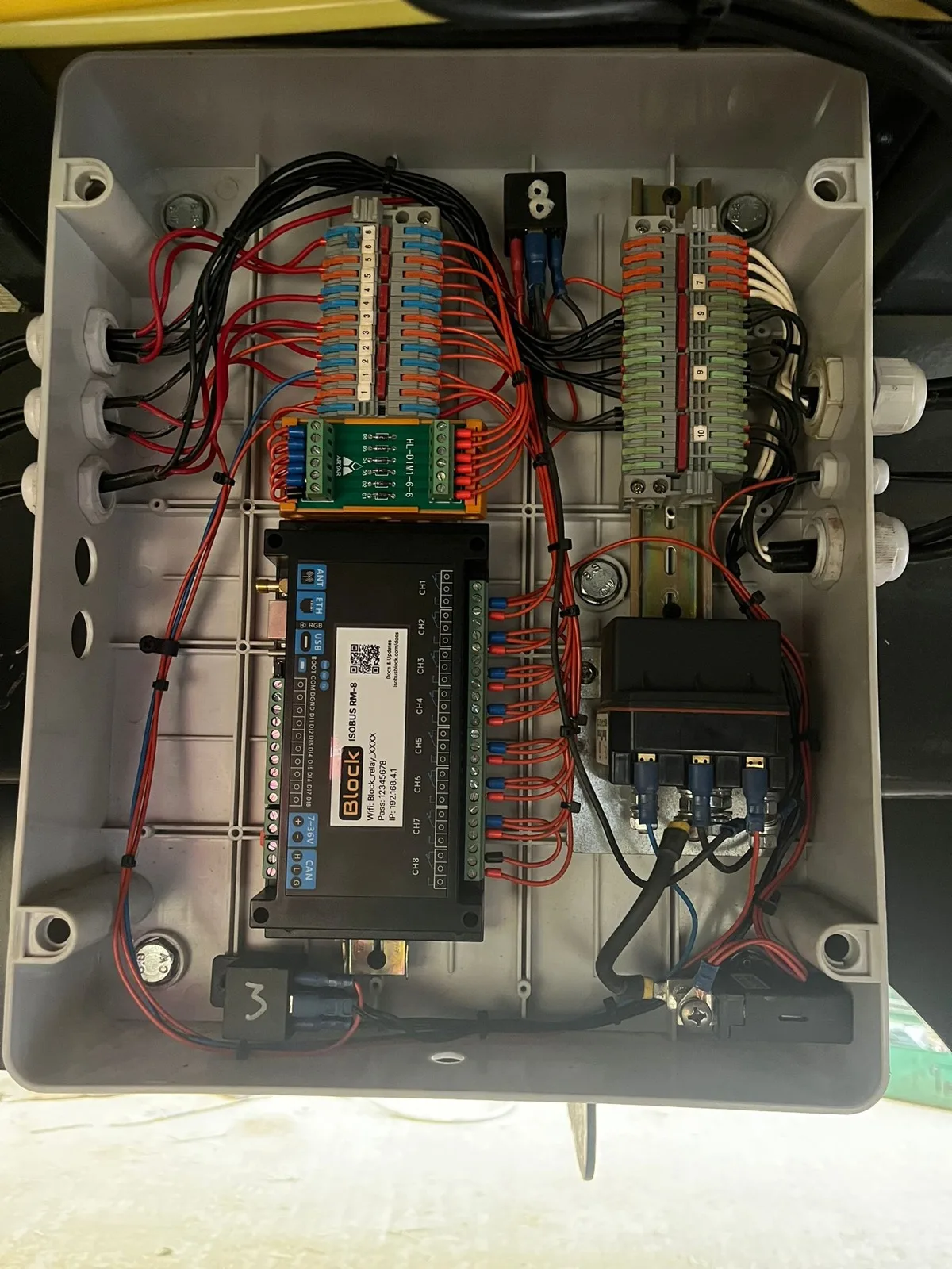 The enclosure open on the trailer: the 8-channel module, two rows of push-in terminal blocks and the wiring to the glands