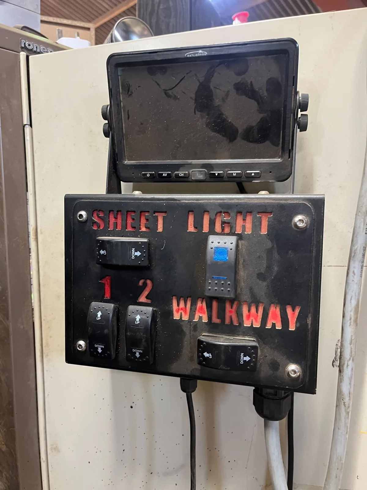 The trailer's old switch box: rocker switches for the sheet and the walkway under a camera monitor